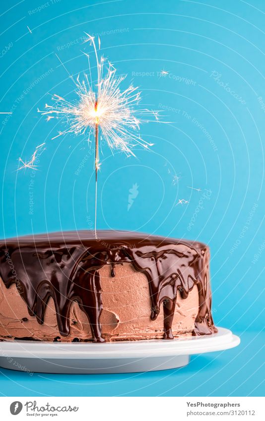 Chocolate glazed birthday cake with a sparkler. New year cake Dessert Feasts & Celebrations Delicious Christmas cake background Birthday cake Blue background