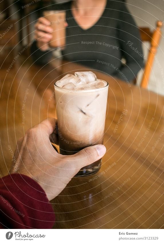 Hand holding coffee, woman drinking in background To have a coffee Drinking Cold drink Milk Espresso Glass Lifestyle Joy Young man Youth (Young adults) Woman