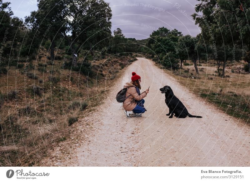 woman using mobile phone outdoors in nature. beautiful black labrador besides. Nature Recklessness Obedient Youth (Young adults) Happy Tongue Green Considerate