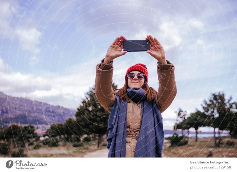 young backpacker woman hiking in nature. Cloudy winter day. Using mobile phone to take a picture Nature Adventure American discovering traveler Green To enjoy