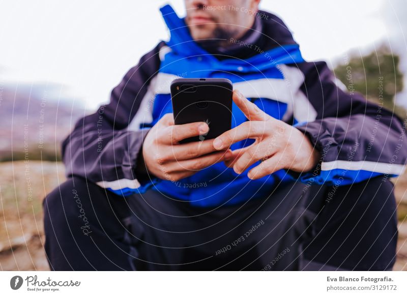 young hiker man using smart phone on top of the mountain. cloudy day Screen smart watch Hiking app ultra workout Fitness Lifestyle Practice device Sports