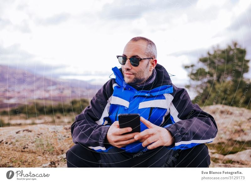 young hiker man using smart phone on top of the mountain. cloudy day Screen smart watch Hiking app ultra workout Fitness Lifestyle Practice device Sports