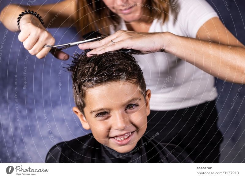 Beautiful boy getting a haircut with scissors Lifestyle Style Hair and hairstyles Health care Child Work and employment Profession Workplace Scissors