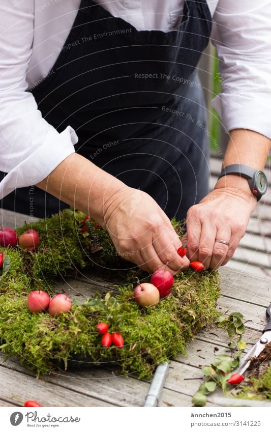 A woman ties and decorates a moss wreath Autumn Wreath Bond Moss Colour photo Nature Plant Green Exterior shot Decoration Leaf Close-up Handicraft Fashioned Red