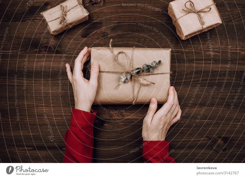 Holiday flatlay of woman's hands holding wrapped presents Vantage point Top Eucalyptus tree Rustic Red New Anniversary Table Birthday Vintage Decoration Package