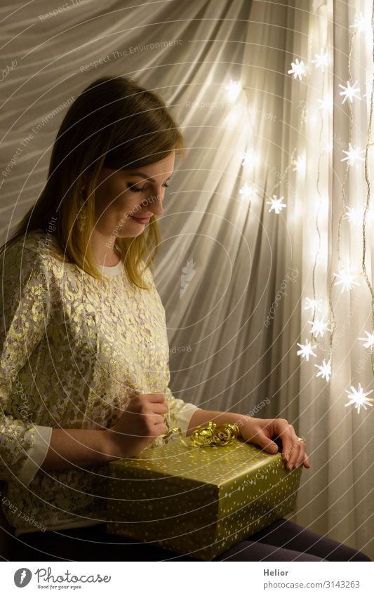 Young woman with a gift in front of a glowing Christmas chain Christmas & Advent Feminine Youth (Young adults) Woman Adults 1 Human being 30 - 45 years Brunette