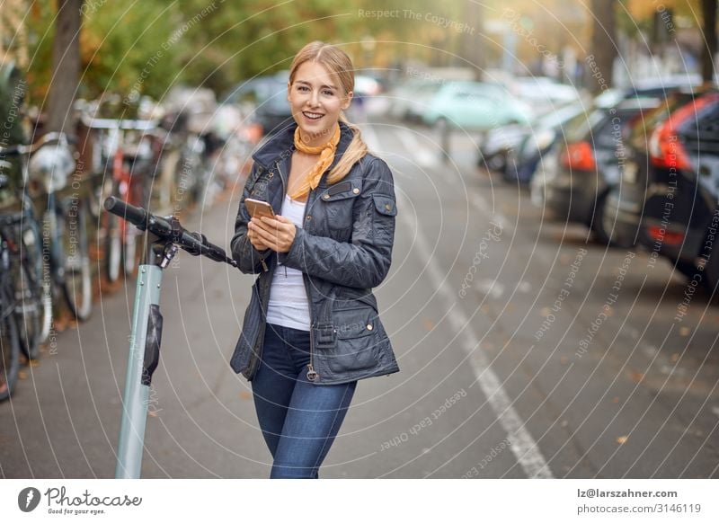 Young woman in the street with e-scooter Lifestyle Happy Beautiful Leisure and hobbies Telephone PDA Technology Woman Adults 1 Human being Autumn Transport