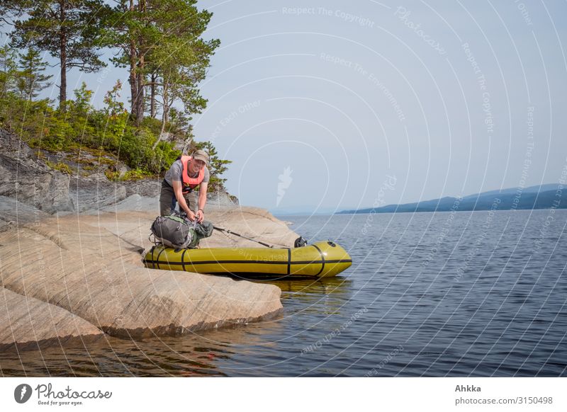 Young man grabs his boat on stone shore of lake Preparation euphoric mood safe harbour awakening Kayak Island Boating trip Grasp bank prepare Far-off places