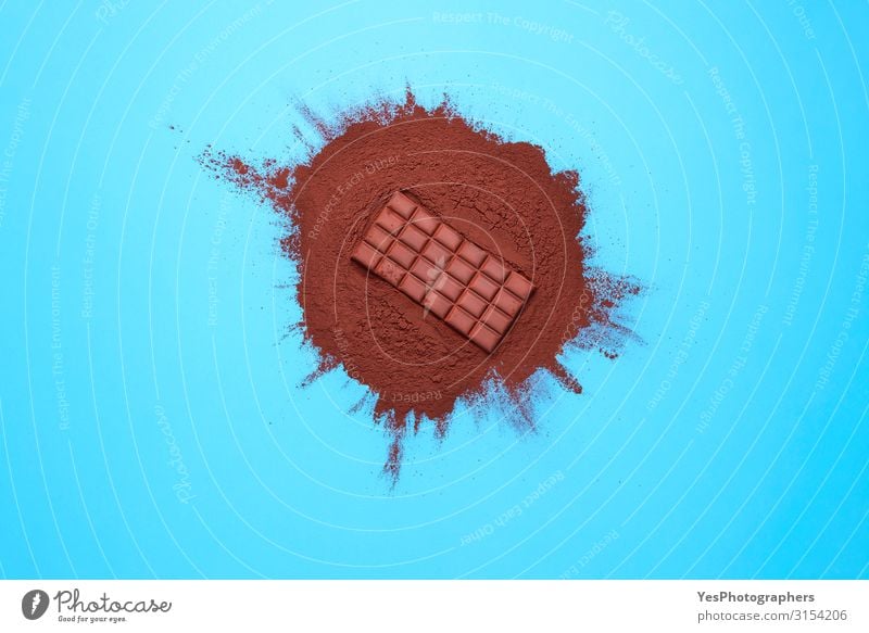 Chocolate bar on cocoa powder pile. Chocolate and ingredients Food Dessert Candy Brown Tradition Christmas cooking above view background Blue background