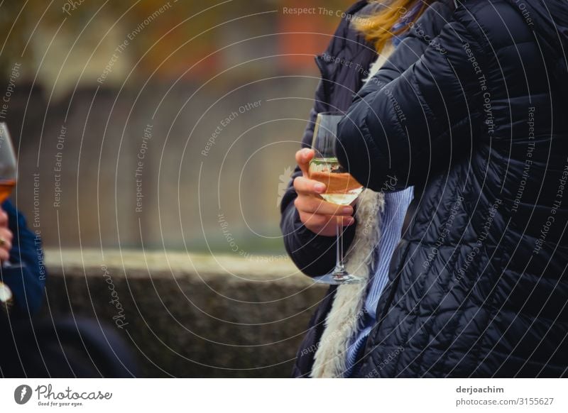 A hand with a wine glass in his hand stands in front of a wall. To the left you can see another wine glass in your hand. Just hang out. Joy Relaxation Trip