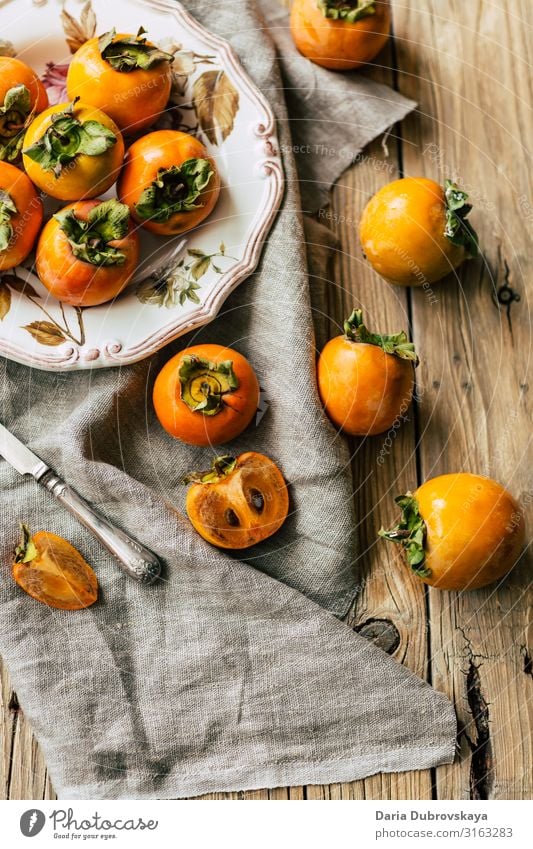 Tasty, ripe persimmons on a beautiful plate and wooden table sweet fresh tasty healthy dessert nutrition orange food raw tree fuyu vegetarian slice freshness