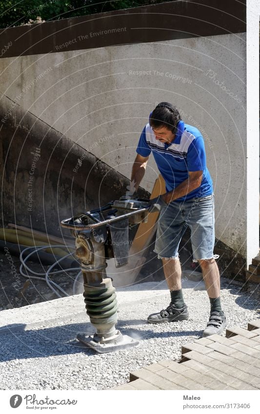 Construction worker works with a tamping machine compact Concentrate compressor Construction site Employer Contract Curbside Work and employment Equipment