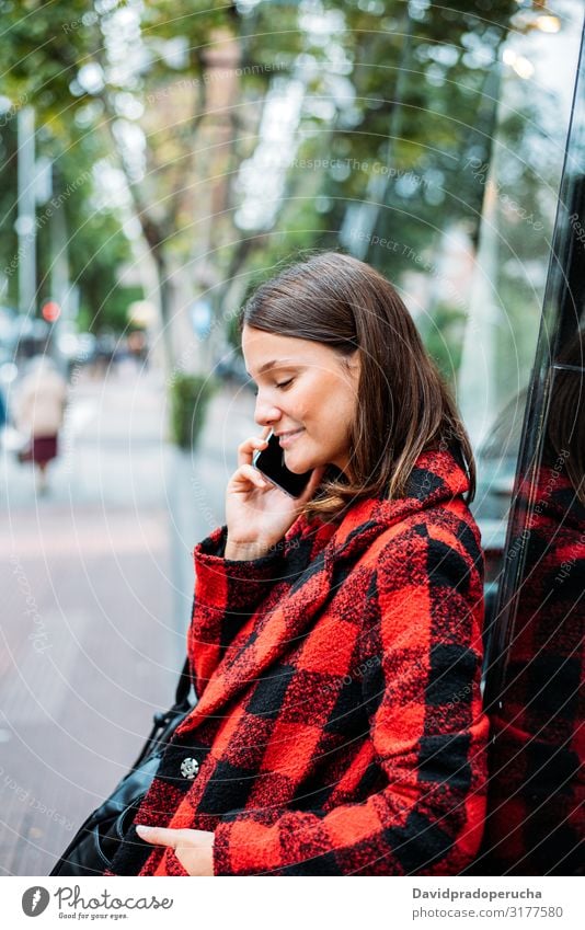 pretty young woman standing on glass on the street using smartphone cell technology smile daylight looking away device gadget conversation outdoors city tail