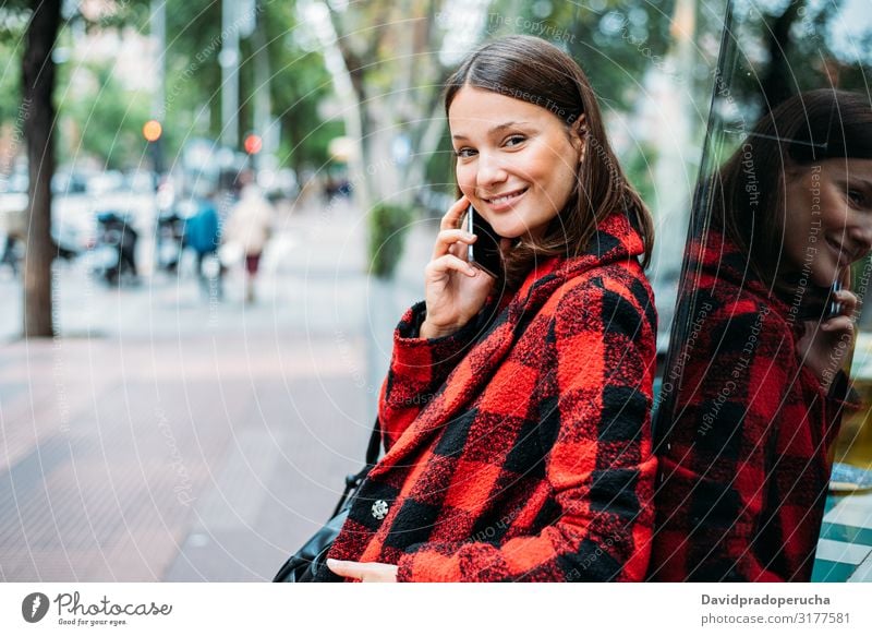 pretty young woman standing on glass on the street using smartphone cell technology smile daylight looking away device gadget conversation outdoors city tail