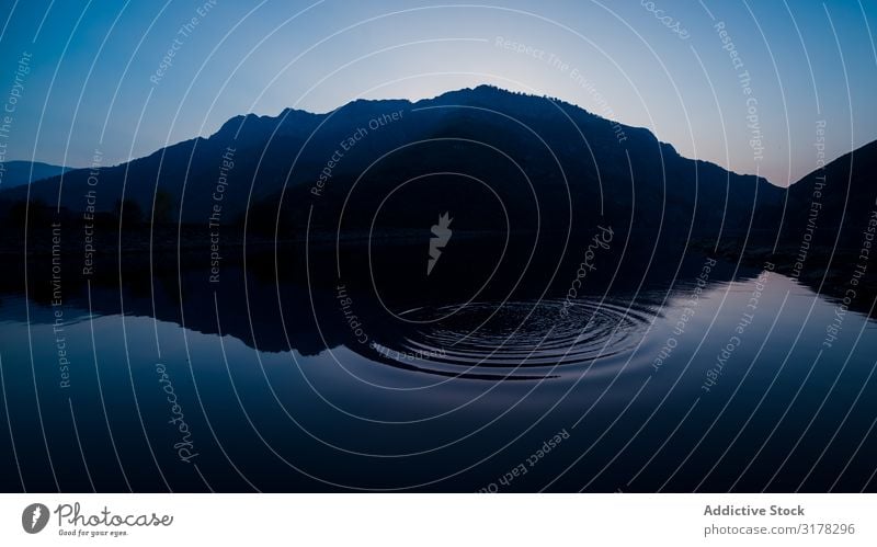 Picturesque view of water surface near amazing rock hills at sunset and blue sky Mountain Water Coast Sky Blue Snow Stone Hill Surface Amazing Heaven Rock