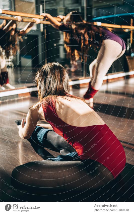 Young dancers training together in studio warming up and flexing in sunlight. Woman Ballet Fitness Practice flexibility stretch Sunlight Action Studio shot