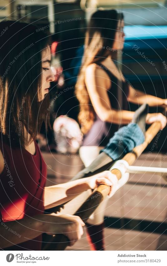 Young ballerinas training in sunny studio standing near mirror with barre. Woman Ballet Stretching Practice Graceful Studio shot dancers Focus on