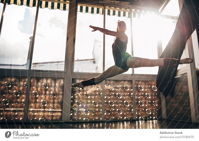 Young slim ballerina jumping above ground in studio flexing legs. Woman Ballerina Jump Splits Ballet pose Movement Acrobatics Gymnastics Dancer