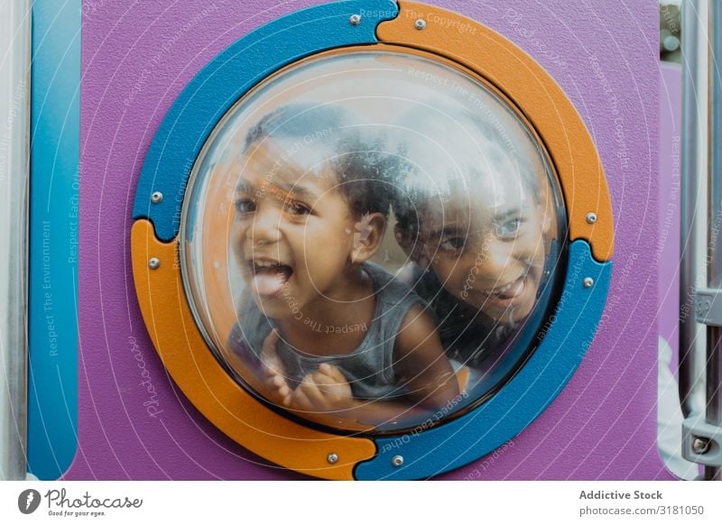 Funny black boys behind porthole on playground Boy (child) Playground Grimace Porthole Happy Action Joy Looking away Child brothers siblings Black Ethnic