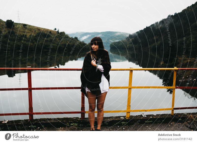 Woman standing looking amazing lake near mountains Stand Fence Lake looking at Mountain Picturesque Water Coast Surface Amazing Vantage point Hill Stone Sky