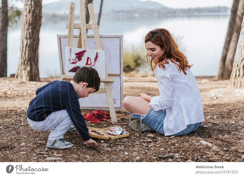 Mother and boy painting near lake Son Painting and drawing (object) Lake haunches Nature Leisure and hobbies Lifestyle Together Woman Boy (child)