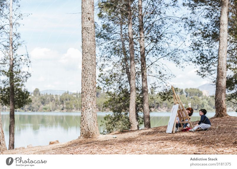 Mother and boy painting near lake Son Painting and drawing (object) Lake haunches Nature Leisure and hobbies Lifestyle Together Woman Boy (child)