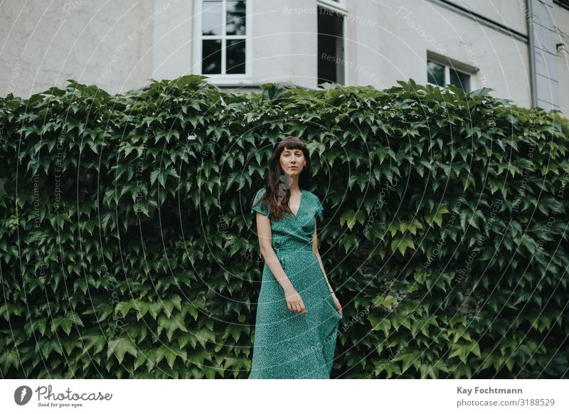 woman wearing an elegant green dress is standing in front of hedge adult attractive beautiful woman charming chic city classic clothing confident europe