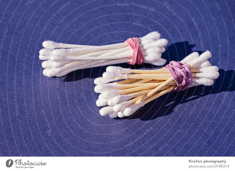 Bamboo cotton sticks versus plastic cotton sticks on purple background. Copy space, zero waste concept, eco-friendly wooden cotton swab safety hygienic ear