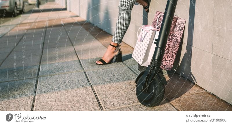 Electric scooter with shopping bags and woman in background. Shopping Elegant Style Internet Human being Woman Adults Feet Transport Street Fashion Modern