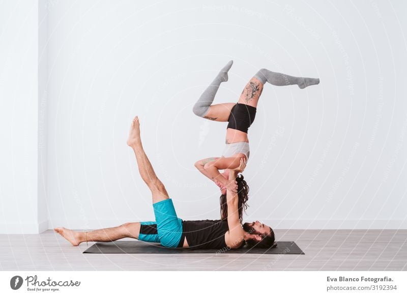 young couple Couple practicing acro yoga in white studio or gym. Healthy lifestyle Yoga Sports Gymnasium indoor Man Power Human being human relationships