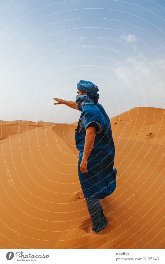 Arabian man in blue clothes walking on a desert dune. Lifestyle Vacation & Travel Tourism Trip Adventure Human being Man Adults 1 18 - 30 years