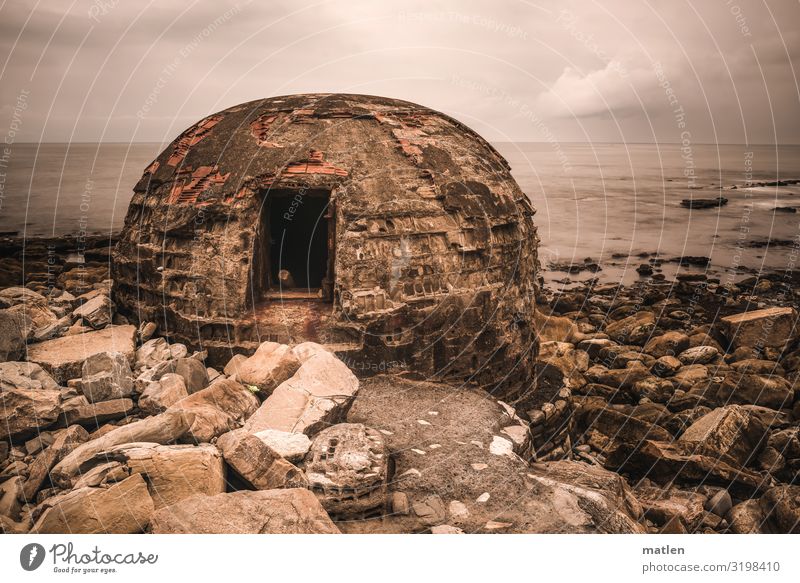 relic Landscape Sky Clouds Horizon Summer Bad weather Beach Ocean Deserted gun emplacement Wall (barrier) Wall (building) Dark Brown Gray Pink Stone Cannon