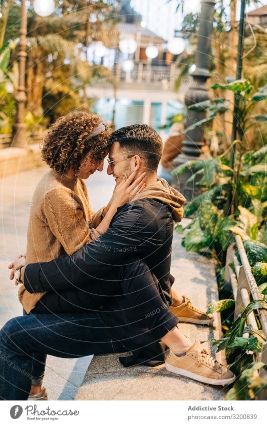 Young couple embracing on bench Couple Embrace Bench touching foreheads Happy Youth (Young adults) Date romantic Sit Street City Man Woman Easygoing tender Town