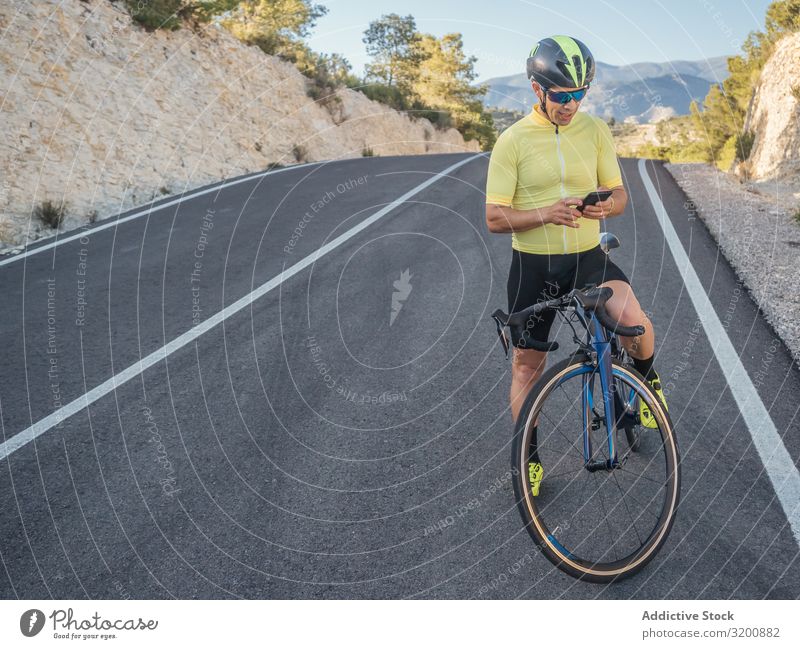 healthy man with smartphone after cycling in a mountain road in a sunny day Leisure and hobbies Athlete Sports Ride Bicycle Racing sports Man Motorcycling