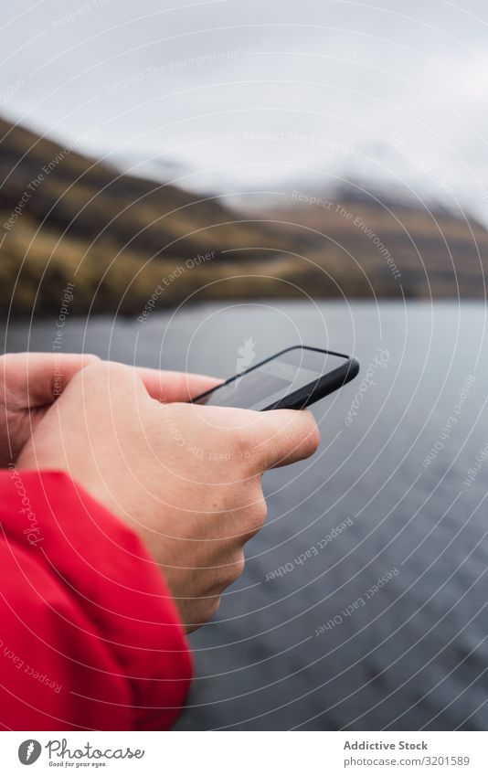 anonymous man using smartphone near a lake in Faroe Island River Green Human being White Telephone Hold over Cellphone messaging Communication Smart Natural