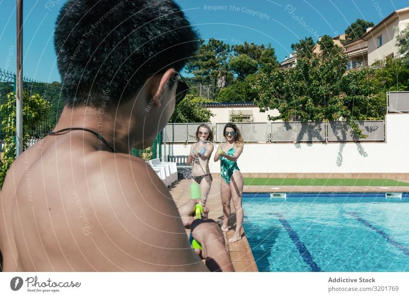 Friends playing with water pistols in the pool Attractive Background picture Beautiful Bikini Caucasian Cheerful Woman Festival Friendship Joy Girl gun Handgun