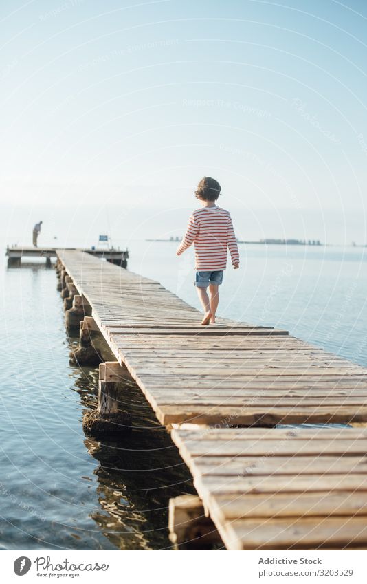 Lonely kid on pier in sunshine Boy (child) Jetty Walking Dream Child Summer Sunlight Vacation & Travel Infancy Water Nature Leisure and hobbies Trip Intellect