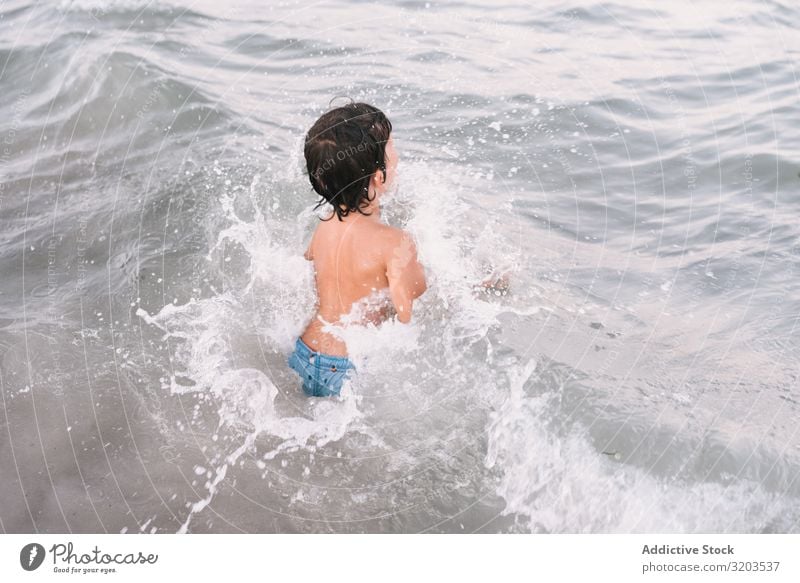 Boy walking in blue water of resort sea Boy (child) Ocean Beach Walking Summer Infancy explore Leisure and hobbies Small Vacation & Travel Joy Sunlight Water