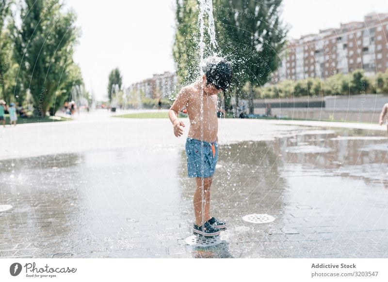 Kid standing in jet of fountain on street Boy (child) Fountain Street Jet Summer Float in the water Stream Water Park Joy Vacation & Travel Town Stand Fresh