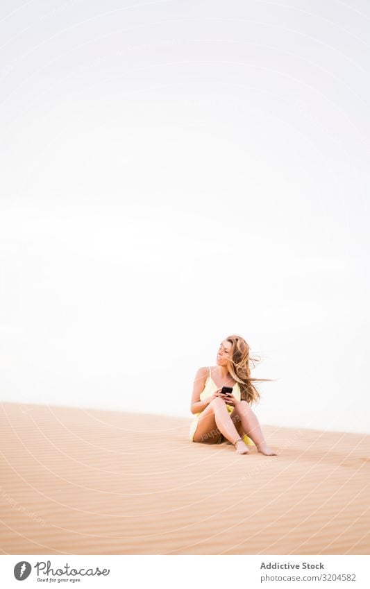 Thoughtful woman using smartphone in desert Woman Desert Considerate Communication Cellphone Technology Vacation & Travel Style Guest Morocco Summer