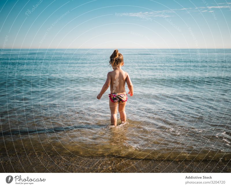 Back view of girl standing in water of seaside Girl Water Playing Cute Toddler Delightful Ocean swimming suit Warmth Beach Sunbeam Infancy Swimming & Bathing