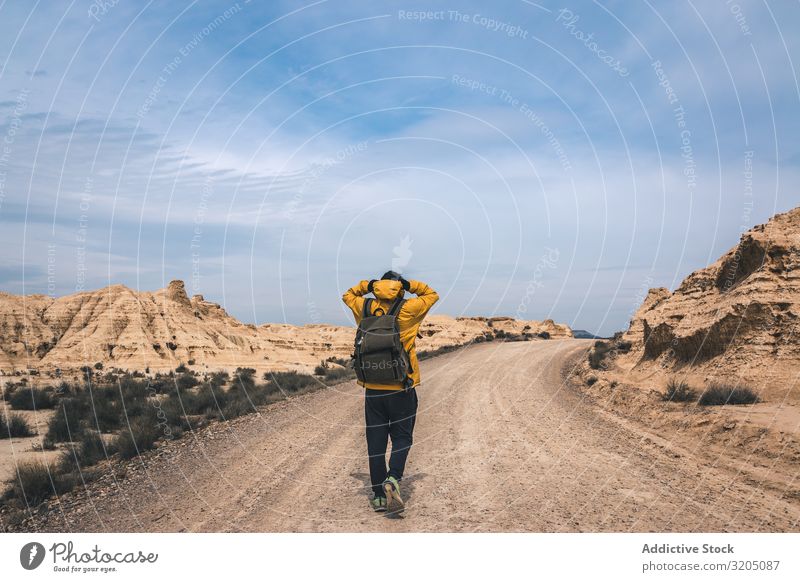 Man walking on road in desert hills Street Desert Hill Landscape Sand Stone Plant Trip Dry Nature Sky Vacation & Travel Hot Destination exploring