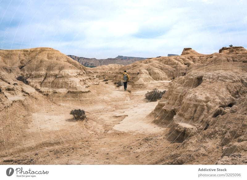 Man walking on amazing landscape of desert hills on background of blue sky Desert Hill Landscape Sand Stone Plant Trip Dry Nature Sky Vacation & Travel Hot