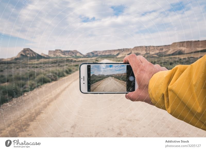 Person taking picture of empty road and desert landscape Man Street taking photo Desert Hill Landscape Sand Stone Plant Trip PDA Dry Nature Sky