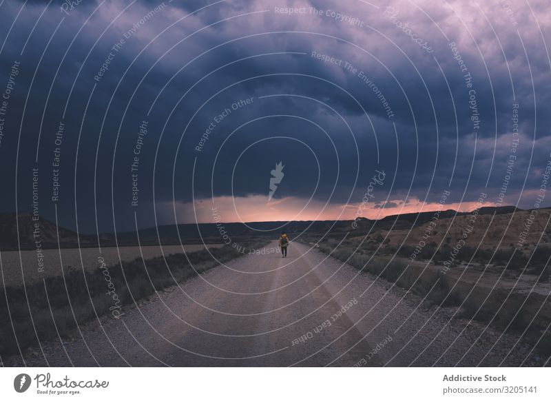 Man standing on road and looking at impressive evening sky Street Twilight Desert Landscape Sand Stone Trip Dusk Nature Sky Vacation & Travel Hot Destination