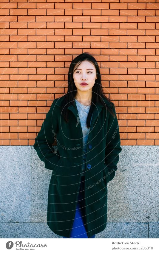 Pensive Asian woman leaning on brick wall Woman Wall (building) Lean Looking away Street City asian Ethnic Rough Relief Surface Lifestyle Leisure and hobbies