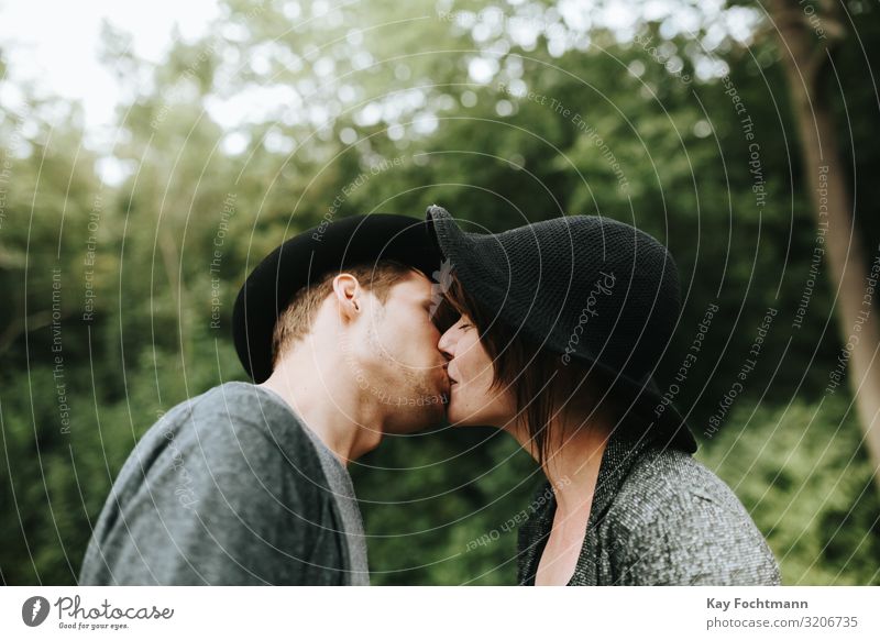 young heterosexual couple wearing hats kissing each other affection bonding casual caucasian charming cute date dating day daytime emotional enjoy enjoyment