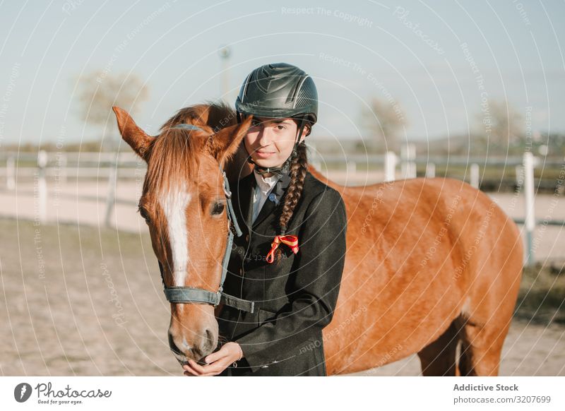 Woman in jockey outfit standing with horse woman stroke animal equestrian teen young pet friend love caress helmet touch beautiful mammal relationship stable