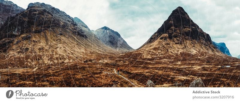 Person walking through picturesque mountains person wind scotland nature cold landscape travel view valley beauty freedom adventure trekking natural tourism