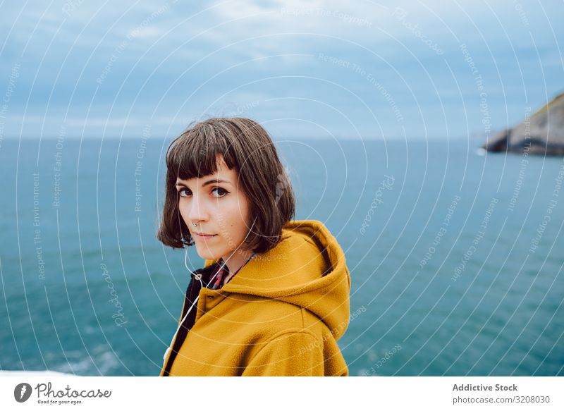 Young woman standing near sea cloudy sky travel jacket warm nature leisure lifestyle female shore coast water ocean blue young trip journey tourism lady glad